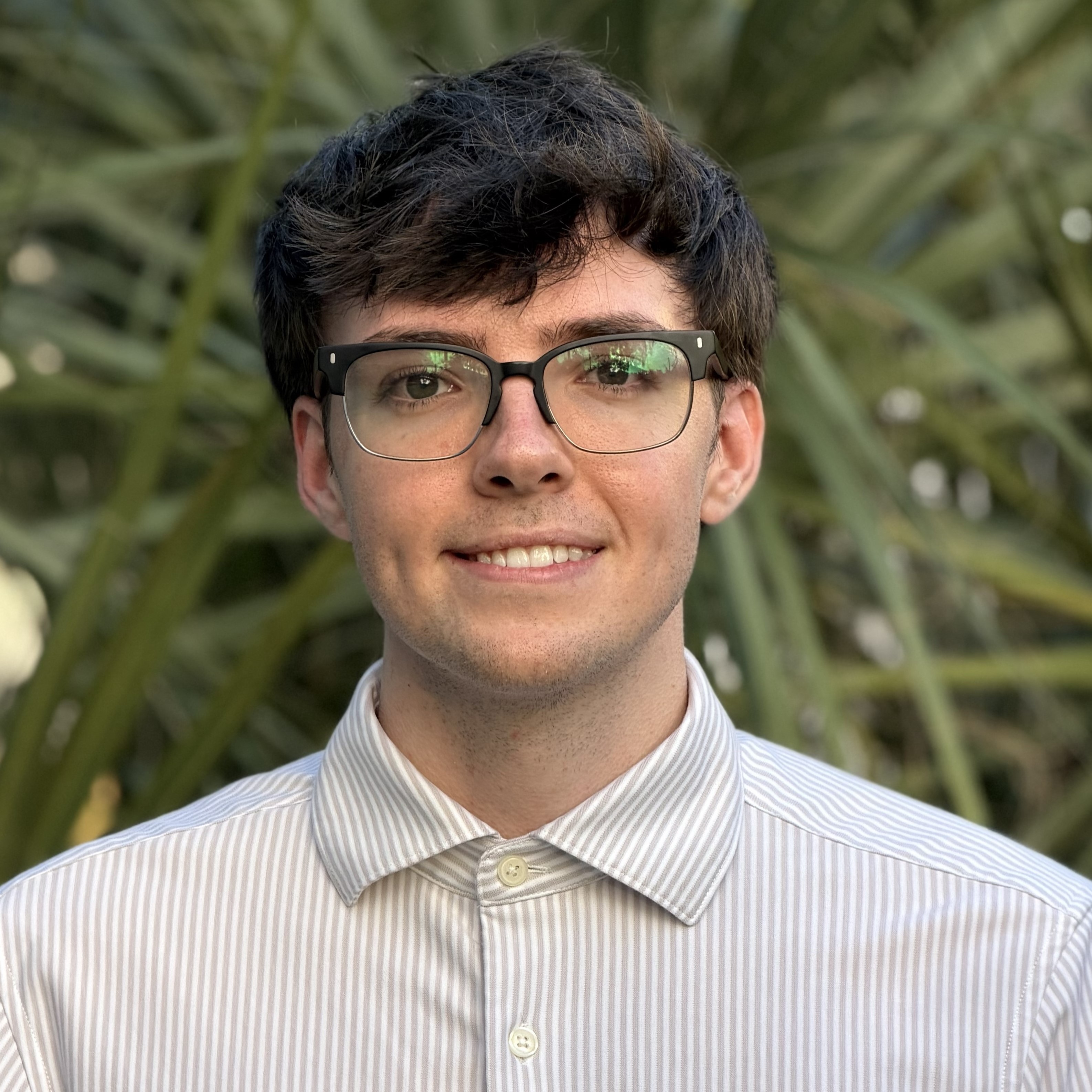 Jeanine White smiling in a red plaid shirt and tortoise shell glasses